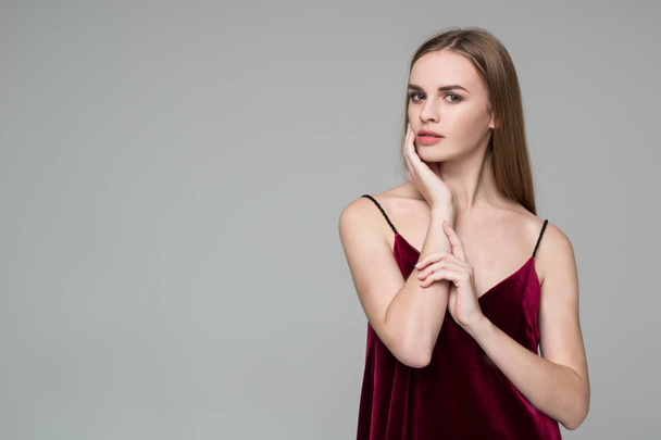 Young model long-haired blond girl in dard red dress poses showing emotions - Foto, afbeelding