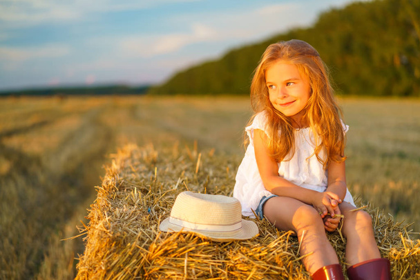 Little girl in a field with hay rolls - Фото, зображення