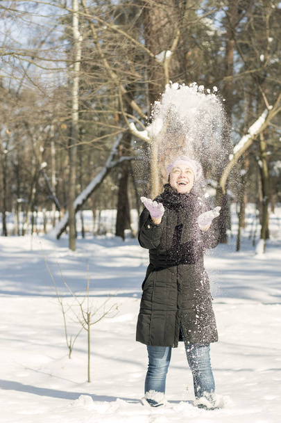 Портрет красивої дівчини, що кидає сніг взимку. Щаслива молода жінка грає зі снігом у сонячний зимовий день. Дівчина кидає сніг у зимовий сніг. Вертикальне фото
. - Фото, зображення
