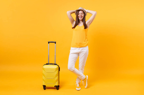 Reiziger toeristische vrouw in zomer casual kleding, hoed met koffer geïsoleerd op geel oranje achtergrond. Vrouwelijke passagier reizen in het buitenland te reizen op weekend uitje. Air vlucht reis concept - Foto, afbeelding