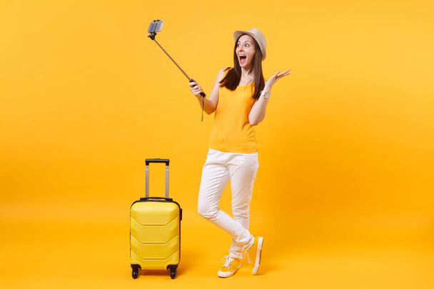 Heureuse femme touristique en vêtements décontractés d'été, chapeau faisant selfie tourné sur téléphone mobile isolé sur fond jaune orange. Passager voyageant à l'étranger pour voyager le week-end escapade. Concept de vol aérien
 - Photo, image