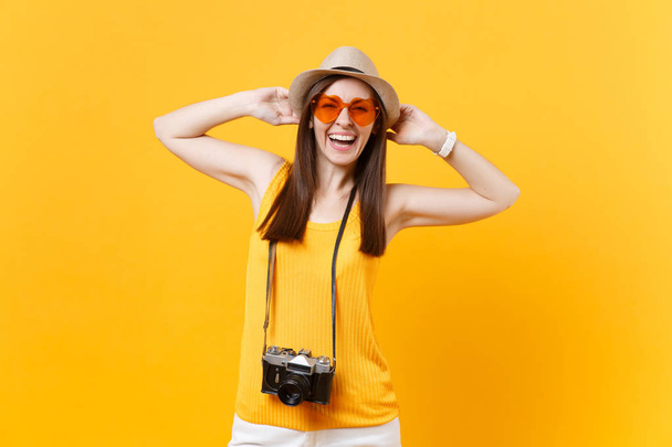 Boldog utas turisztikai nő nyári alkalmi ruha, kalap retro vintage fotó kamera elszigetelt, a sárga-narancssárga háttérrel. Lány utazik külföldre utazik, a menekülés hétvégén. Légi járat koncepció - Fotó, kép