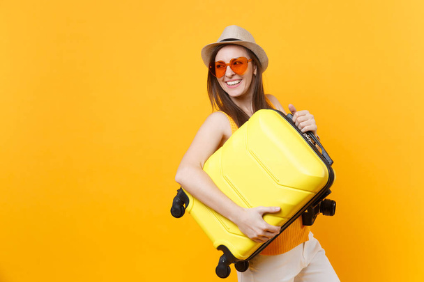 Matkailija turisti nainen kesällä rento vaatteita, hattu matkalaukku eristetty keltainen oranssi tausta. Naispuolinen matkustaja matkustaa ulkomaille viikonloppuisin. Lentomatkan käsite
 - Valokuva, kuva