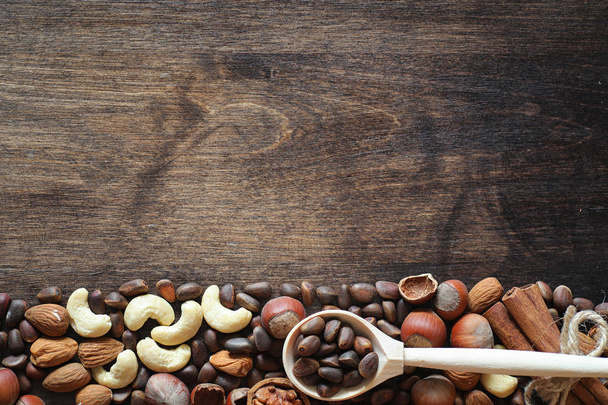 Eri pähkinöitä puupöydällä. setri, cashew, hasselpähkinä, saksanpähkinä
 - Valokuva, kuva