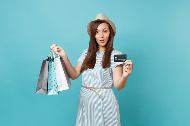 Muotokuva kaunis valkoihoinen nainen kesämekko, olki hattu tilalla paketteja pussit ostamisen jälkeen, pankkikortti eristetty sininen pastelli tausta. Kopioi tilaa mainokselle
 - Valokuva, kuva
