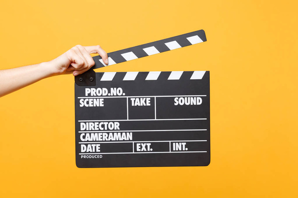 Close up female holding in hand classic director clear empty black film making clapperboard isolated on yellow orange background. Cinematography production concept. Copy space for advertising - Foto, Imagen