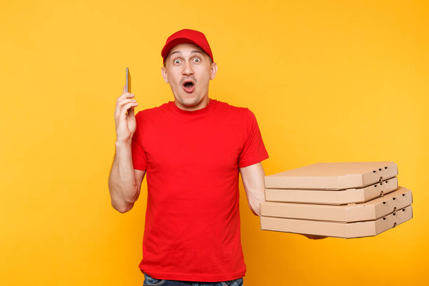 Курьер в футболке с красной кепкой заказывает итальянскую пиццу в пустых пустых пустых коробках на желтом фоне. Курьер-пиццамен мужского пола разговаривает на макете мобильного телефона. Концепция обслуживания
 - Фото, изображение