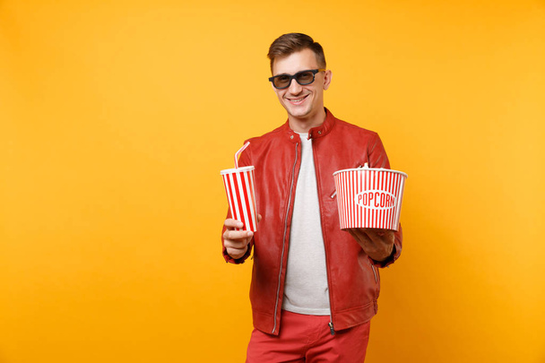 Portrait jeune homme en 3D lunettes, veste en cuir, t-shirt regarder film, tenant pop-corn, tasse de soda isolé sur fond jaune vif. Personnes émotions sincères concept de style de vie
. - Photo, image