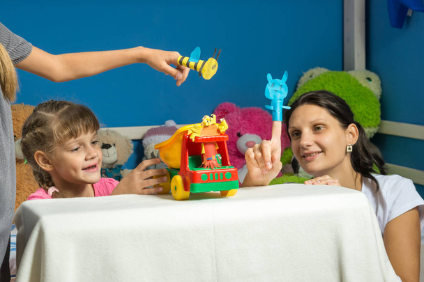 An enthusiastic mother plays with daughters in a self-made finger puppet theater - Photo, Image