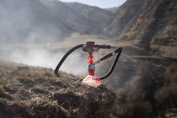Hookah, traditional arabic waterpipe, direct sunset light, outdoor photo. Mountain background. Outdoor. Empty space. - Photo, Image