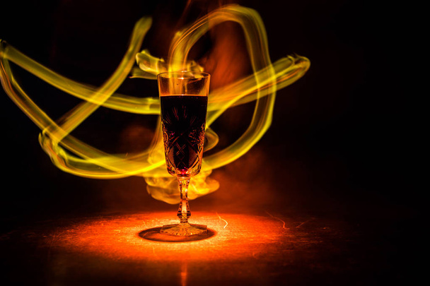 Wine glass in fire concept. One glass of red wine with burning fire on black background. Selective focus. Empty space - Foto, afbeelding