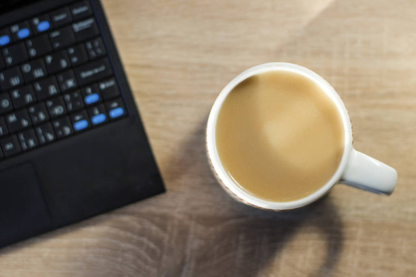 hrnek na kávu s mlékem vedle notebooku, práce doma, ploché rozložení - Fotografie, Obrázek
