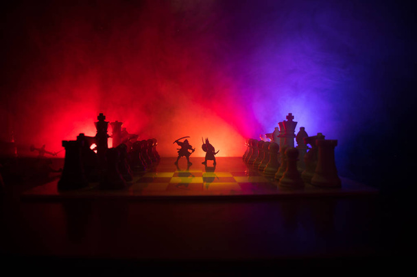Middeleeuwse slag scène met de cavalerie en infanterie op een schaakbord. Schaken bordspel concept van bedrijfsideeën en concurrentie en strategie ideeën Chess cijfers op een donkere achtergrond met rook en mist. - Foto, afbeelding