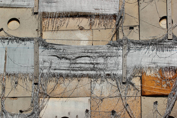 Isolamento de parede esfarrapado velho, sacos rasgados de nylon e pranchas de madeira como fundo
 - Foto, Imagem