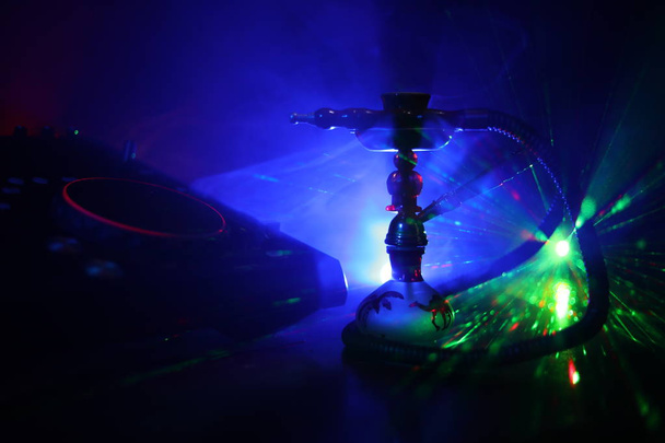 Concepto de club de fiesta de Shisha. Mezclador de DJ con fondo de discoteca oscura con elegante shisha oriental. Enfoque selectivo
 - Foto, Imagen