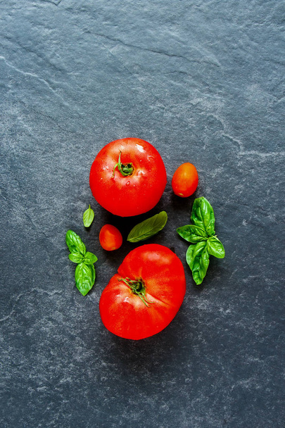 Tomato and basil leaves on dark copy space background flat lay, top view - Foto, imagen