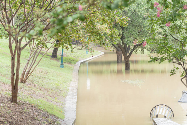Flut Wasser Verbreitung Dallas Fort Wert Bereich, Texas, Vereinigte Staaten, überschwemmte Hundeabfallstation und Outdoor-Stahl Müllbehälter in der Nähe Bürgersteig des Flussufers Nachbarschaft - Foto, Bild