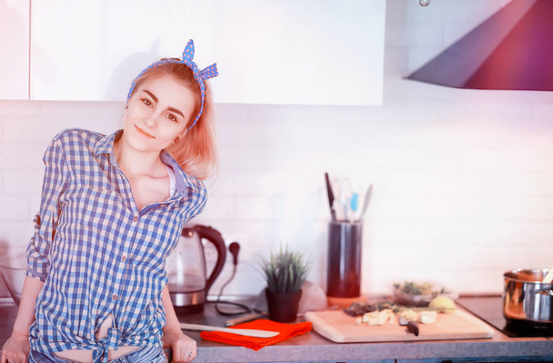Ένα χαριτωμένο νεαρή κοπέλα στην κουζίνα προετοιμάζει τροφίμων - Φωτογραφία, εικόνα