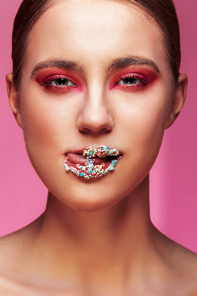 beautiful girl with candies on pink backgroound - Фото, изображение