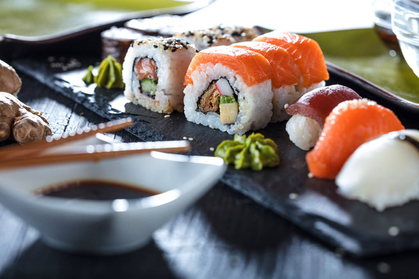 Sushi Set sashimi and sushi rolls served on stone slate - Фото, изображение