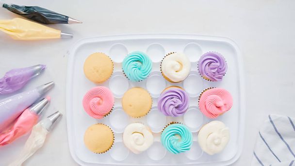 Βήμα-βήμα. Σεφ ζαχαροπλαστικής σωληνώσεις βούτυρο κρέμα ζαχαροαλοιφή σε μονόκερος cupcakes για μικρό κόμμα κορίτσι γενεθλίων. - Φωτογραφία, εικόνα