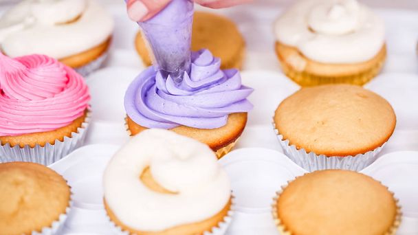 Lépésről lépésre. Cukrászati chef csővezeték vaj tejszín, kicsi lány születésnapi partiján Egyszarvú cupcakes cukormáz. - Fotó, kép