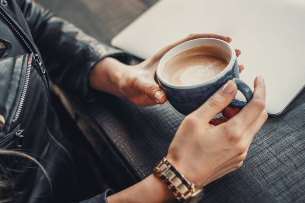 Молодая женщина в кафе держит чашку кофе в руках. Обеденный перерыв
 - Фото, изображение