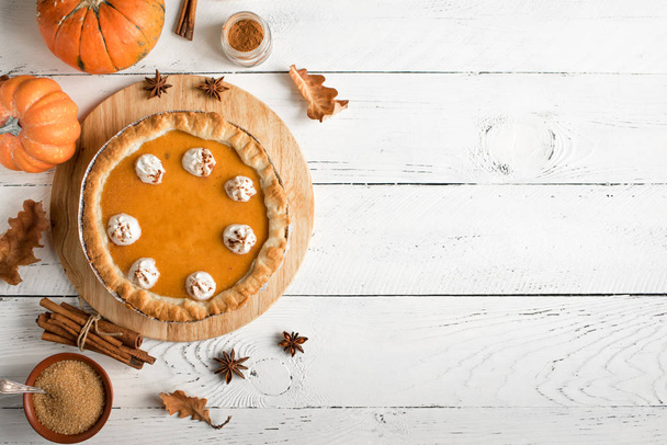 Pumpkin Pie with whipped cream and cinnamon on white wooden background, top view. Homemade pastry for Thanksgiving traditional Pumpkin Pie. - Valokuva, kuva