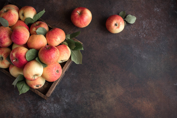 Red apples in wooden box. Organic red apples with leaves on rustic background, copy space. - Foto, Imagem