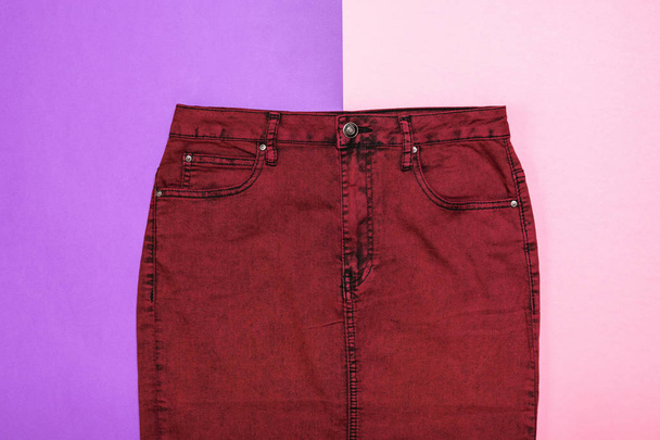 Burgunder Jeansrock auf zweifarbigem Hintergrund. modische Jeans-Damenbekleidung. Jeans-Frauenkleidung auf farbigem Hintergrund. - Foto, Bild