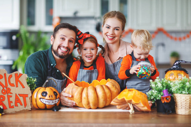 happy Halloween! family mother father and children cut a pumpkin for holiday home - Photo, Image