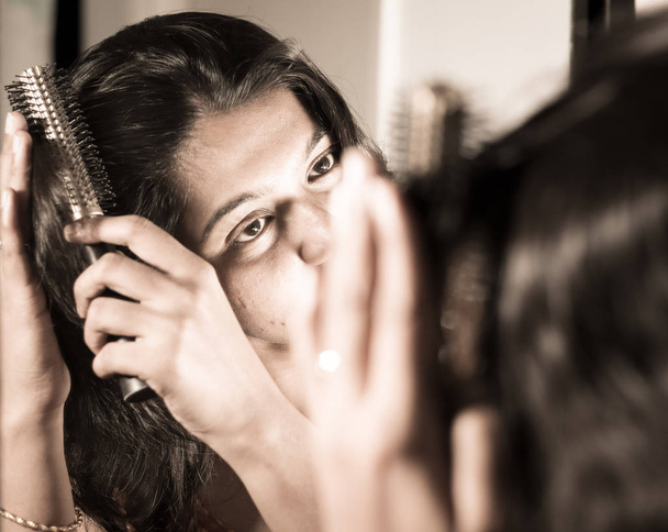 Dame kämmt ihre Haare mit Haarbürste am Spiegel. - Foto, Bild