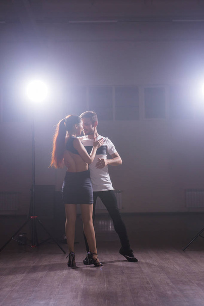 Geschickte Tänzer, die im dunklen Raum unter dem Licht und Rauch des Konzerts auftreten. sinnliches Paar, das einen künstlerischen und emotionalen zeitgenössischen Tanz aufführt - Foto, Bild