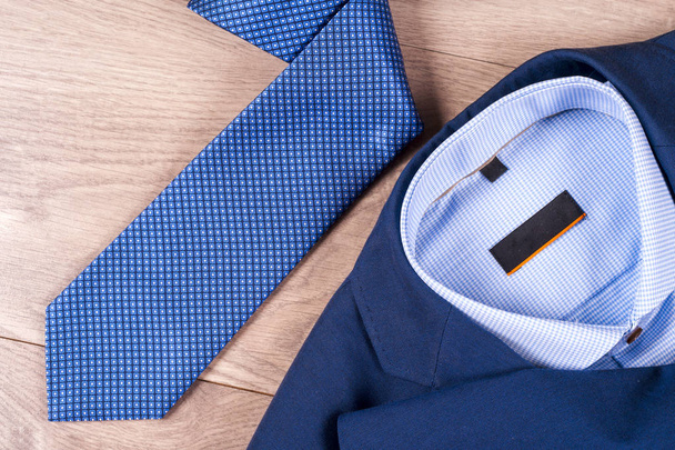 set of classic mens clothes - blue suit, shirts, brown shoes, belt and tie on wooden background. - Φωτογραφία, εικόνα