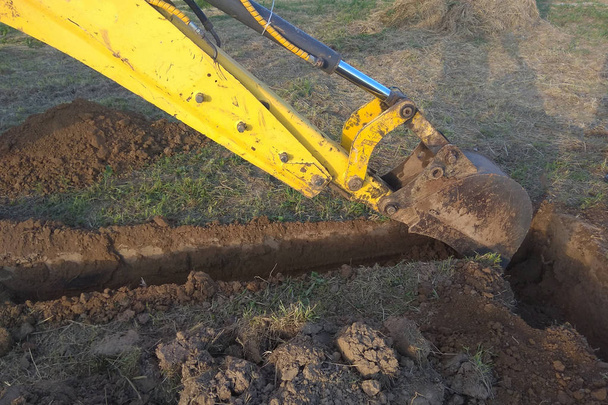 Una excavadora de trabajo cava una zanja en una casa de campo
 - Foto, imagen