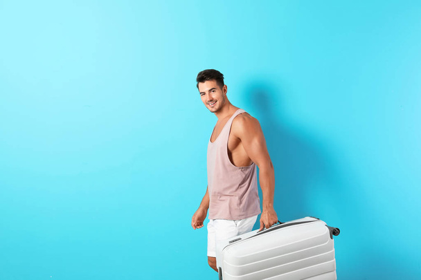 Young man with suitcase on color background. Space for text - Φωτογραφία, εικόνα