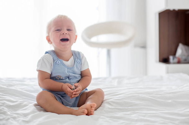 Toddler baby boy, playing with dummy, crying unhappy for the pacifier in children bedroom - Foto, immagini
