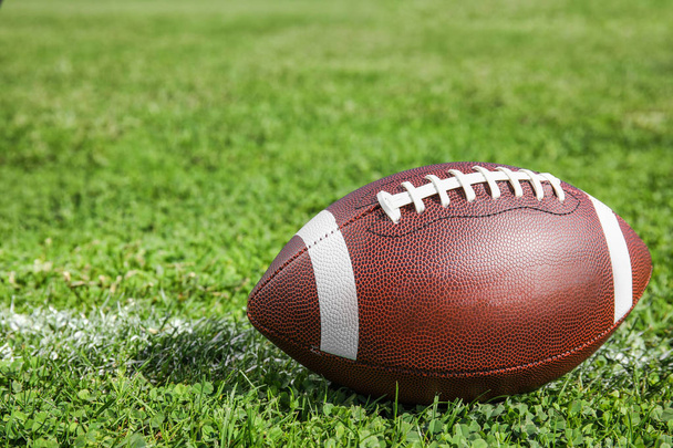 Μπάλα για το αμερικανικό ποδόσφαιρο στο γρασίδι φρέσκο πράσινο πεδίο - Φωτογραφία, εικόνα