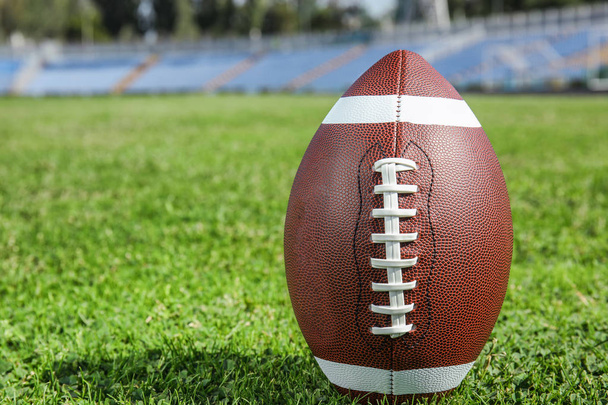 Мяч для американского футбола на свежей зеленой траве. Пространство для текста
 - Фото, изображение