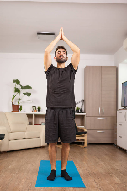 Fit man practicing yoga in the living room - Photo, Image