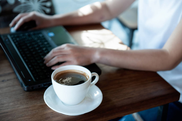 Office girl hand on laptop keyboard and mouse.Coffee cup on the table. - Photo, image