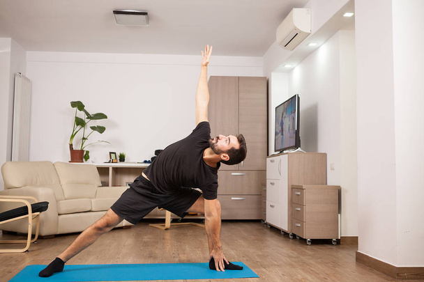Hombre atractivo probando lado extendido Yoga posa en el piso de su casa
 - Foto, Imagen