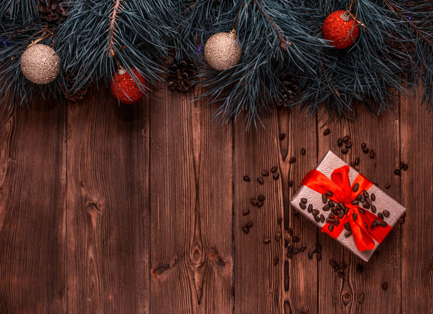 A box with a Christmas gift and pine nuts on a brown wooden background, pine paws and Christmas balls, a New Year gift, copy space - Foto, immagini