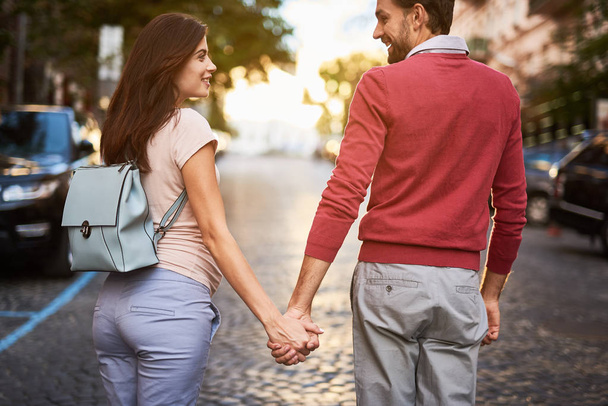 Loving couple holding hands while walking down the road - Φωτογραφία, εικόνα