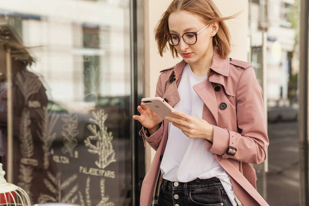 Happy smiling businesswoman using modern smartphone device, successful female entrepreneur using cellphone wireless connection walking along the street, young woman browsing mobile phone outside - Foto, Bild