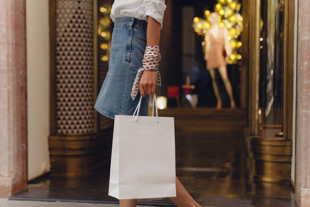 Mockup of white paper shopping bag. Attractive girl doing shopping in shopping mall. Space for your logo or design. Clothes and dress on the background - Fotoğraf, Görsel