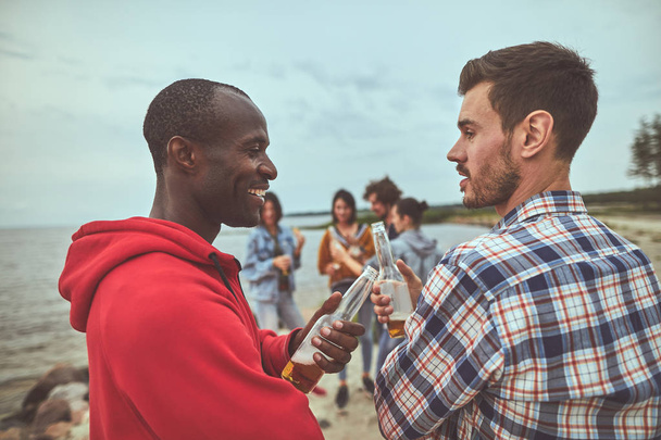 Двоє друзів говорять під час вечірки на пляжі
 - Фото, зображення