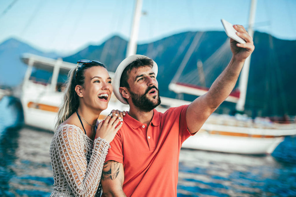 Couple in love, enjoying the summer time by the sea, make selfie photo with phone. - Фото, изображение