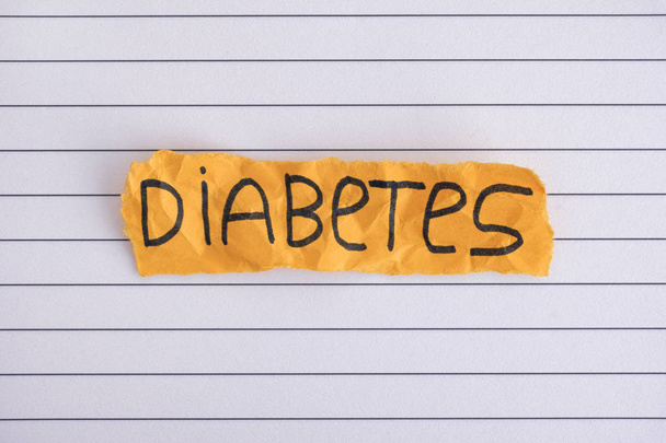 Torn piece of yellow paper with the word DIABETES. Close up. - Foto, afbeelding
