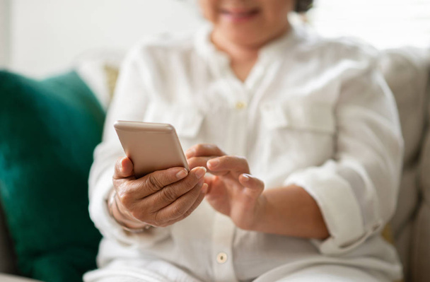 Happy Asian Senior Woman using smart phone at her house. Having fun. - Photo, image